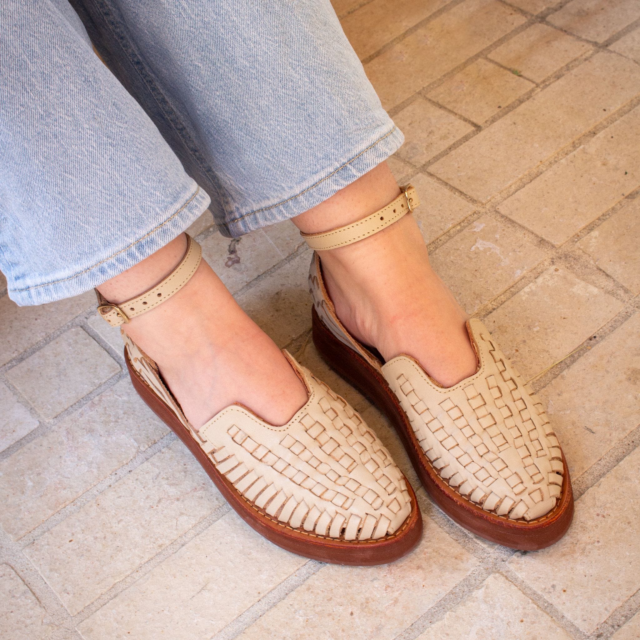 Paula porte les Carmen Grège aux pieds, mettant en avant la bride cheville et le tressage quadrillé de la paire.
