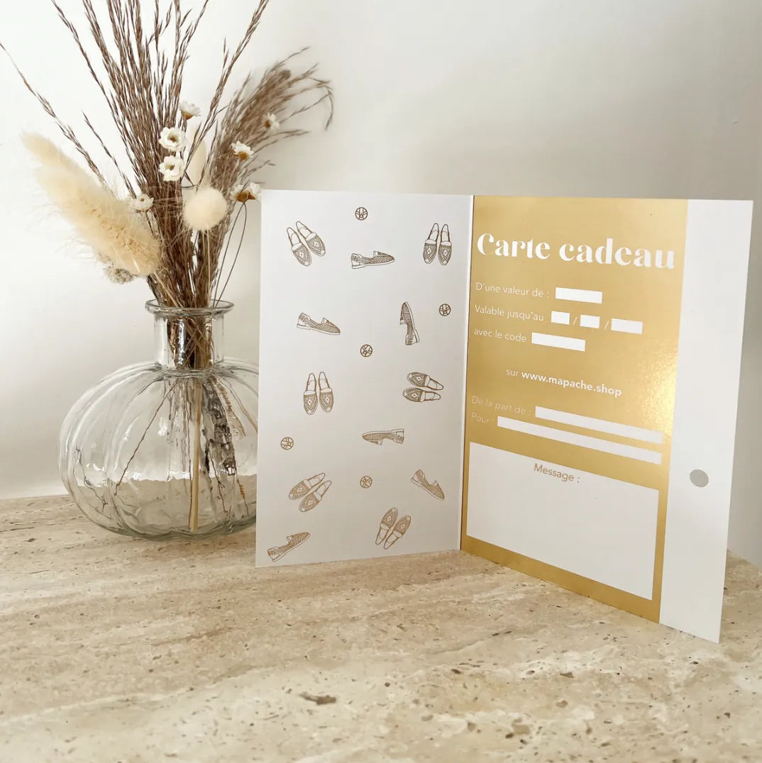 Une carte ouverte montrant les champs à remplir sur une commode en marbre à côté d'un pot de fleurs transparent.