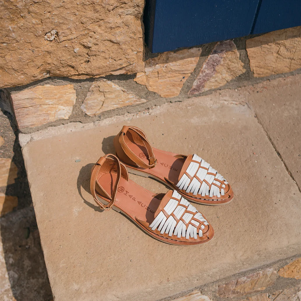 Les Huaraches Carlotta Camel Blanc sont posées sur une marche en pierre au soleil.