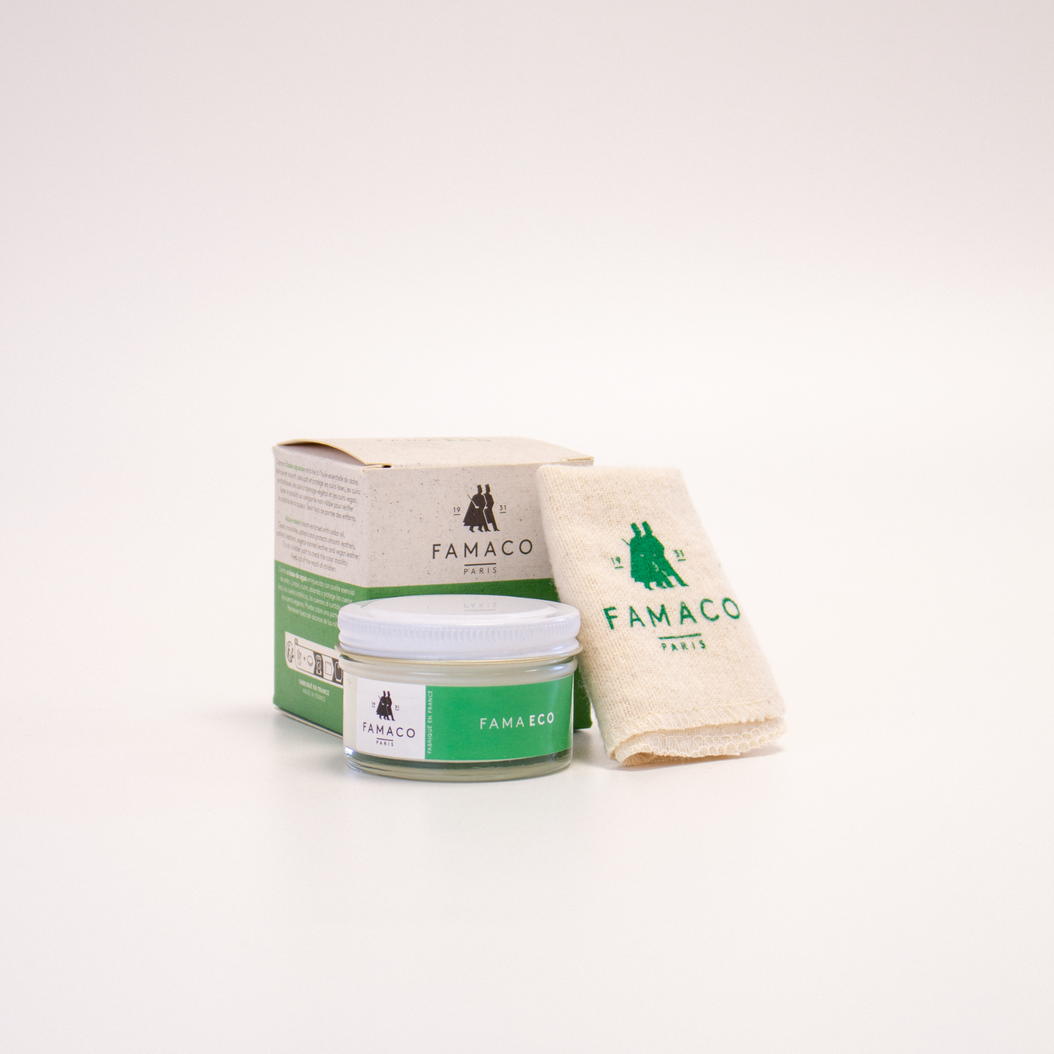 Le pommadier FAMA ECO de FAMACO est placé à côté du chiffon doux fourni, avec son emballage en carton disposé derrière, sur un fond blanc.