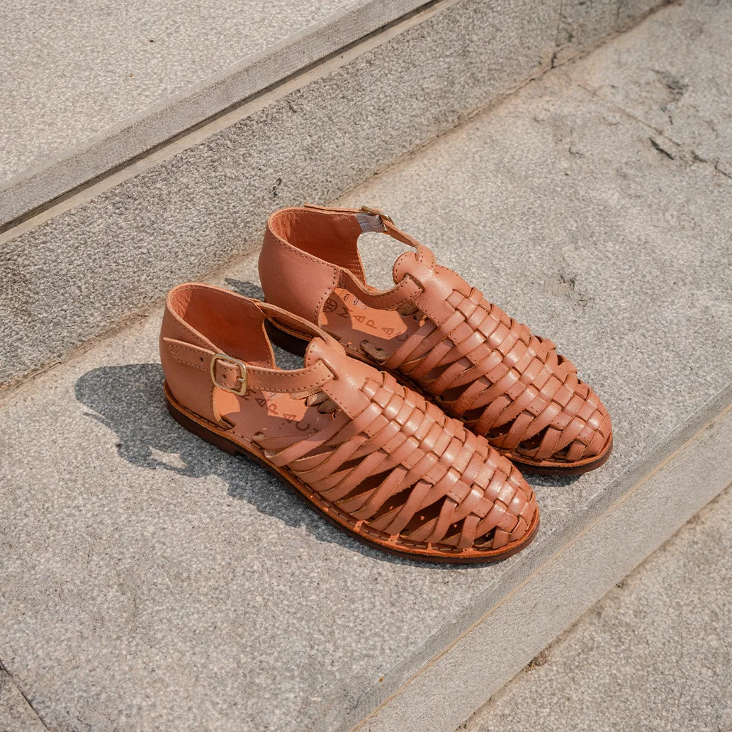 Les Huaraches Medusa Camel sont posées sur des marche en béton gris.