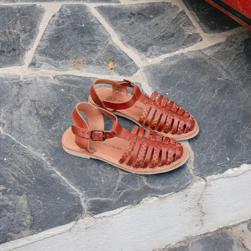 Les Sandales Paloma Tabac sont posées sur un sol en ardoise noire.