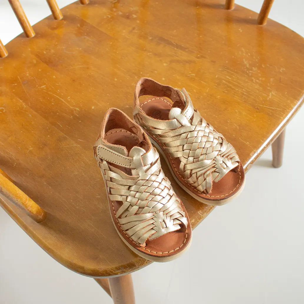 Les Sandales Sandalita Champagnes sont posées sur une chaise en bois au dessus d'un sol blanc.