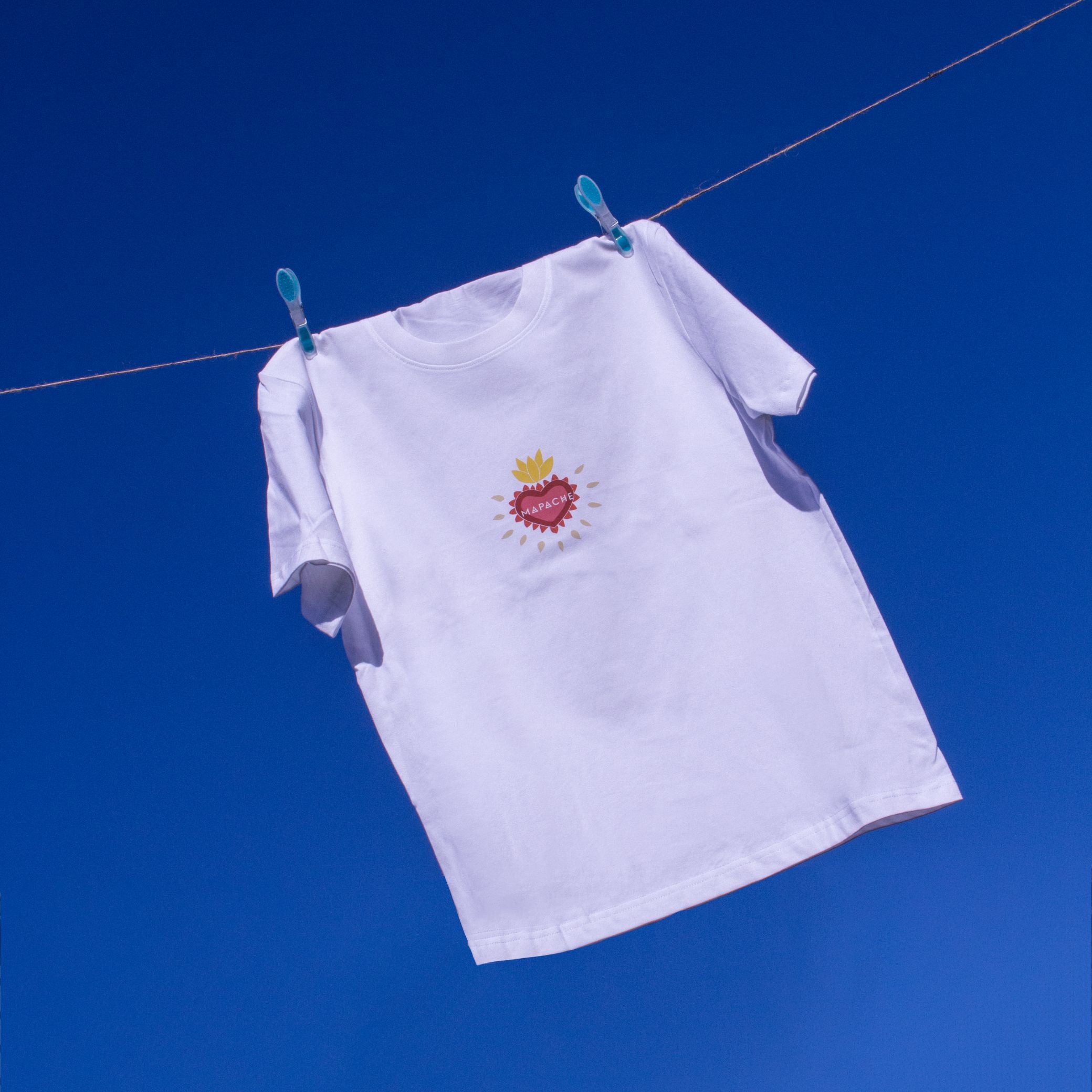 T-shirt blanc à col rond avec le nom "Mapache" imprimé au centre, accompagné d’un cœur stylisé aux motifs ethniques.