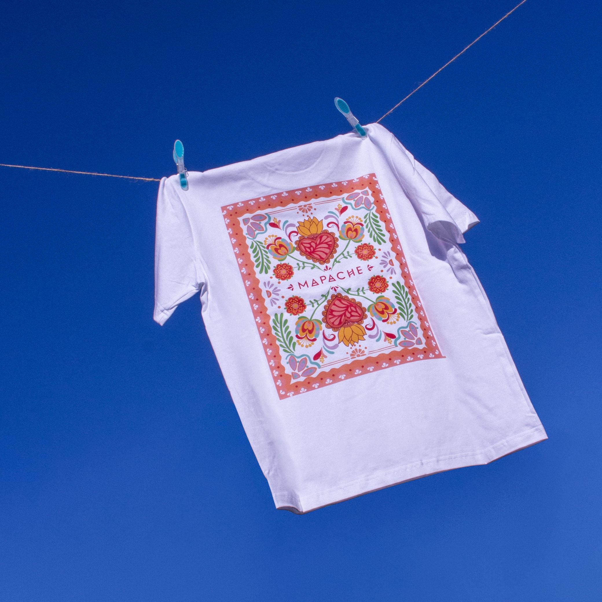 T-shirt blanc avec un grand visuel imprimé dans le dos, représentant un rectangle rempli de fleurs et de cœurs dans un style graphique ethnique.